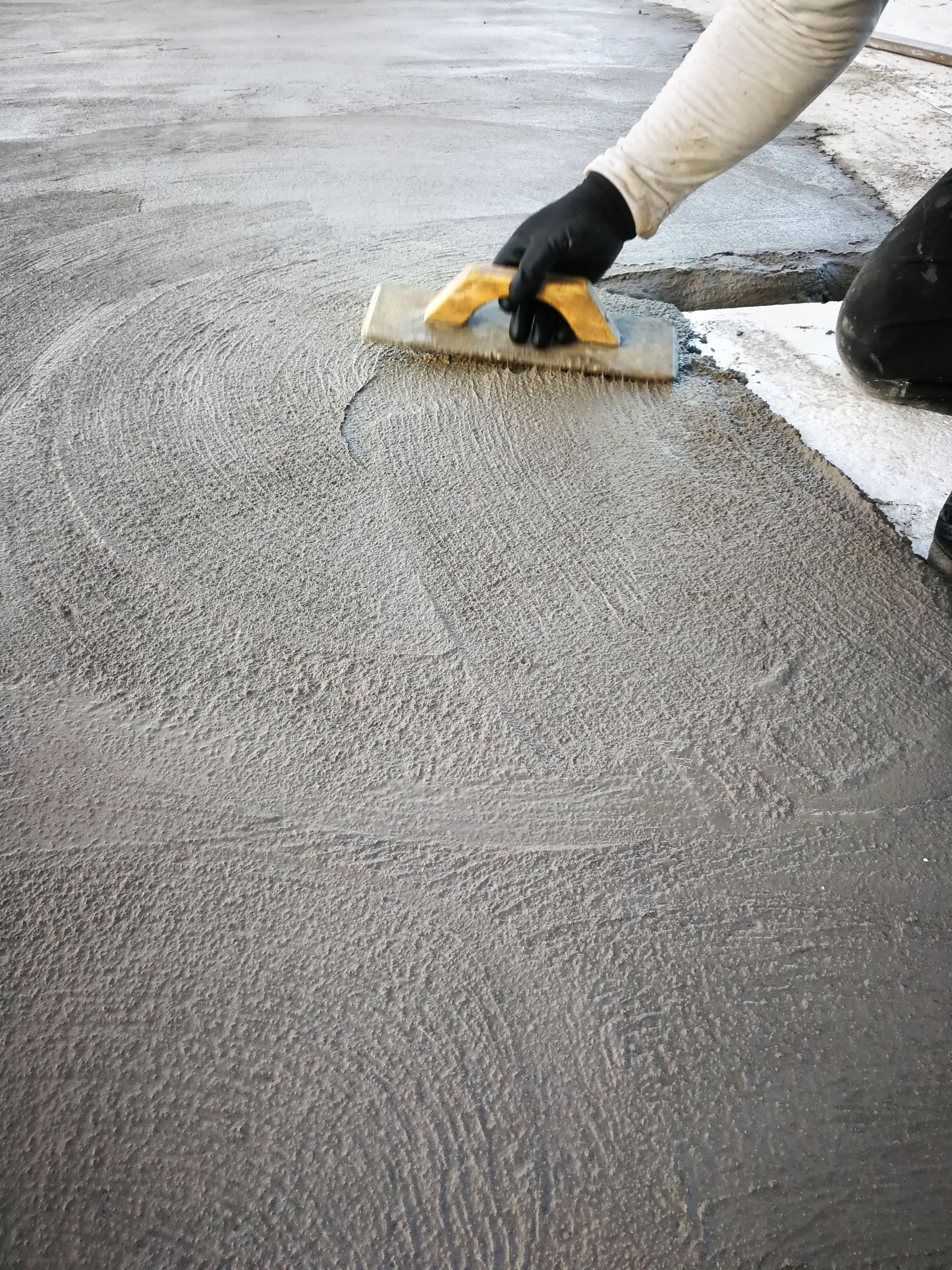 Bricklayer smoothes out fresh cement with a trowel.